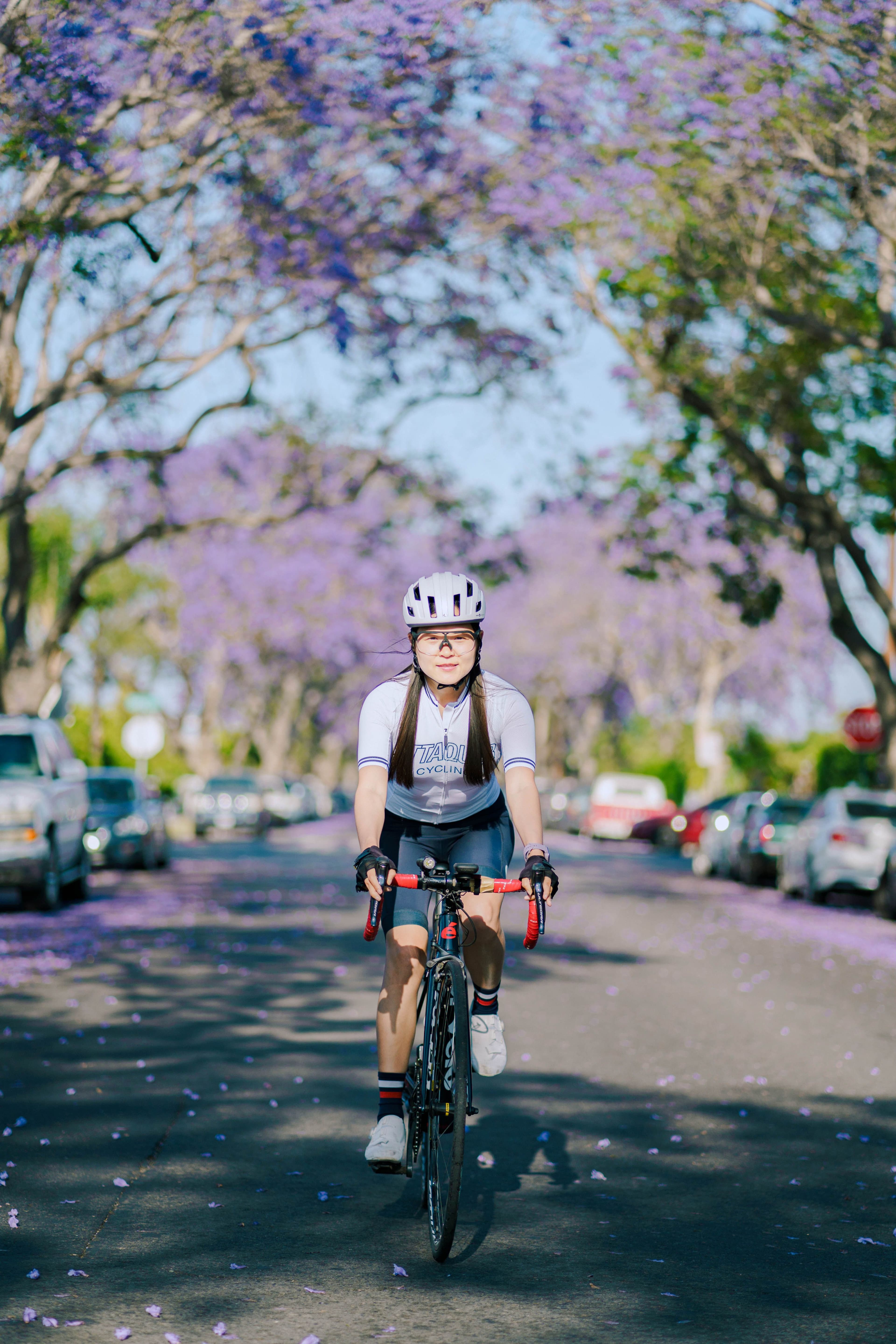 Cycliste de face dans une rue bordée d'arbres en fleurs